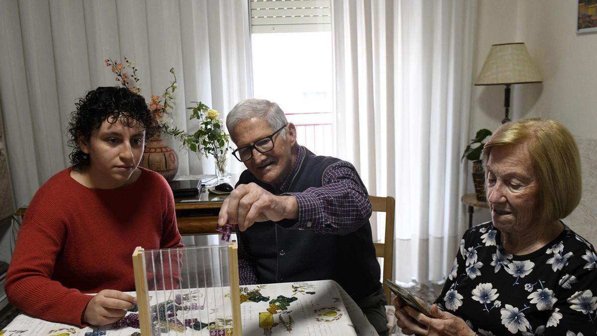 La estudiante Juana Salamanca y José Sánchez practican juegos de mesa mientras que María Soto consulta su teléfono móvil.