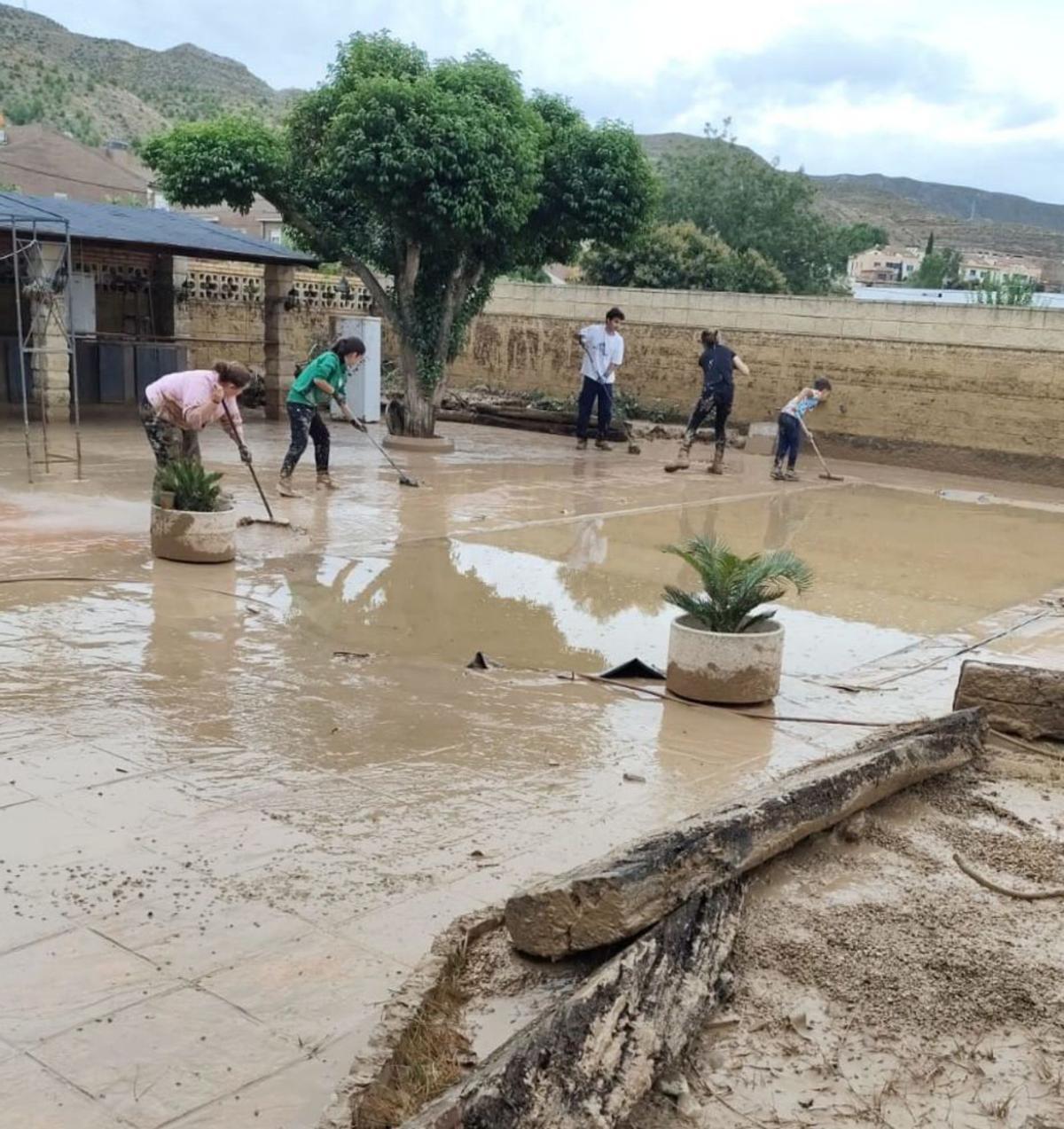 Varios vecinos realizan labores de limpieza en Cadrete. | EL PERIÓDICO