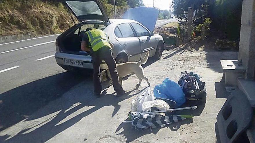 Un agente registra el coche de los detenidos con un perro adiestrado en busca de estupefacientes. // FdV