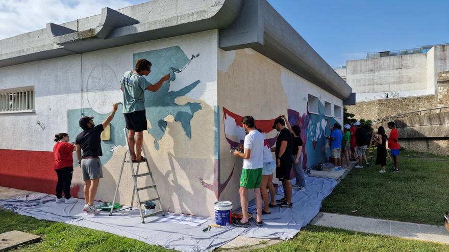 Voluntarios y usuarios pintan, ayer, el mural en la base de Cruz Roja. |   // LOC