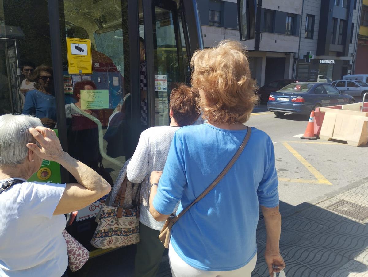 Un bus con las puertas cerradas y viajeros de la línea Laviana-Villa que se quedaron en tierra