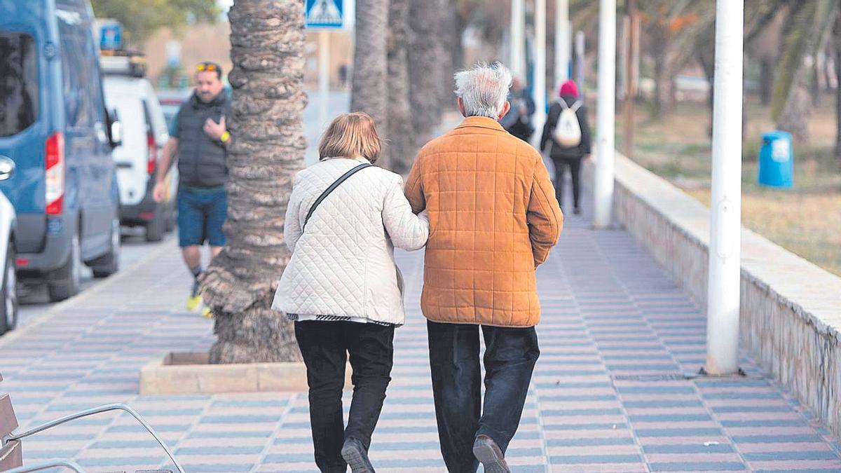 Dos personas mayores, caminando por la calle.