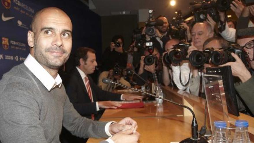 Pep Guardiola, acompañado por Sandro Rosell, objetivo de fotógrafos y cámaras de televisión, al inicio de la rueda de prensa en la que anunció su salida del Barça. | efe