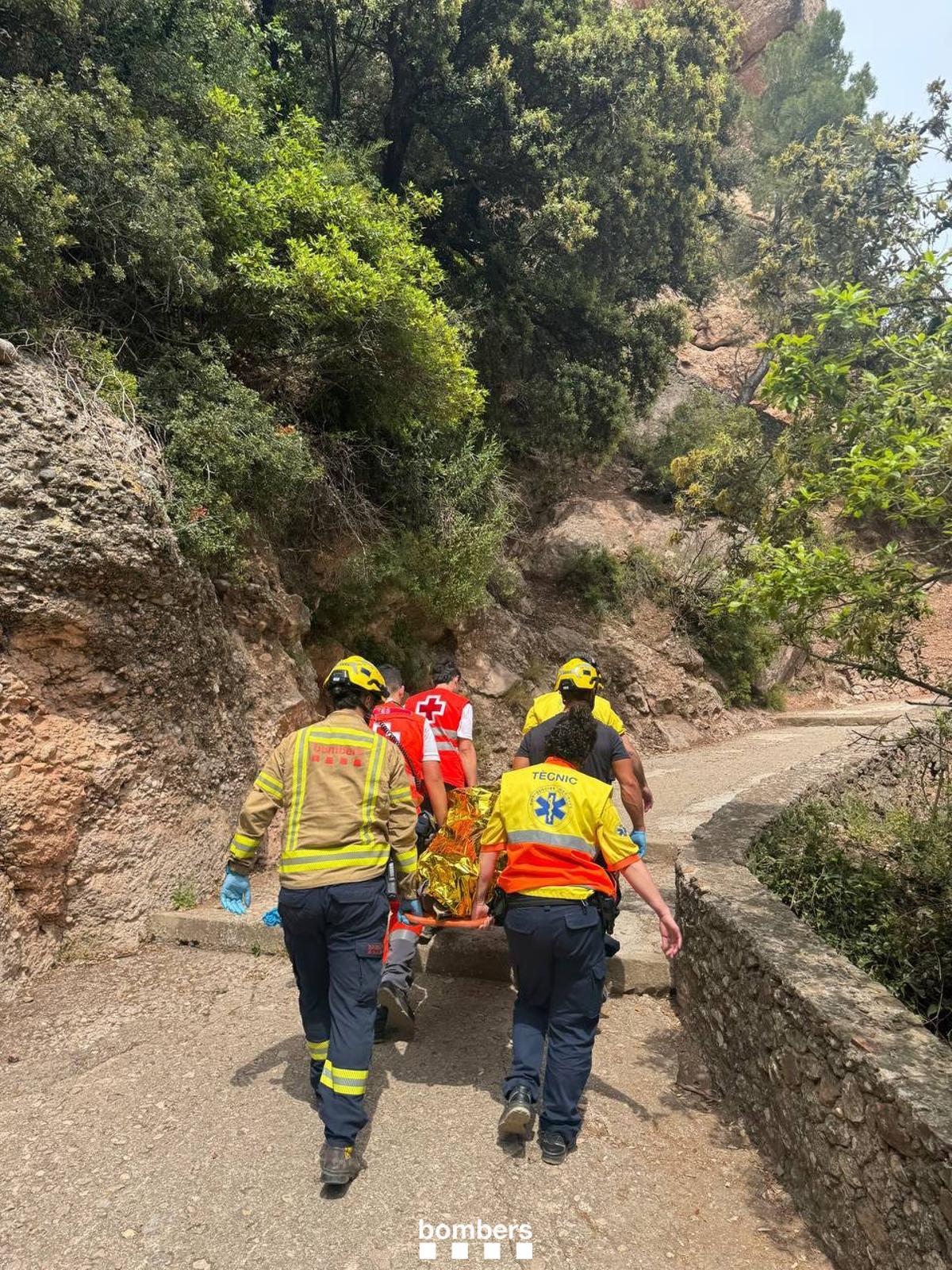 Els equips d'emergència traslladen la dona amb la llitera fins la zona del Monestir