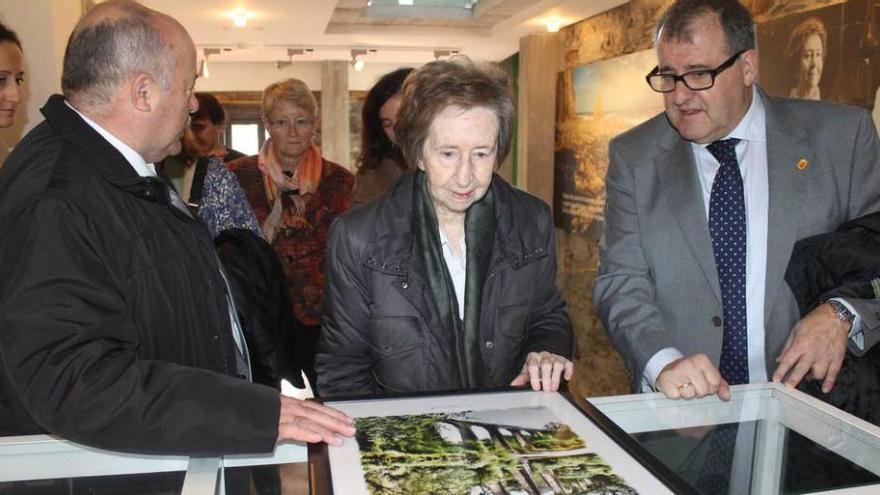 Margarita Salas observa una fotografía del viaducto de Canero, junto a Gumersindo Cuervo (izquierda) y el alcalde de Valdés, Simón Guardado.