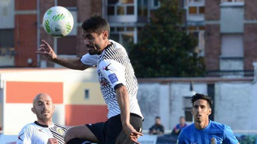 Noel Alonso despeja el balón con Óscar Pérez a su lado.