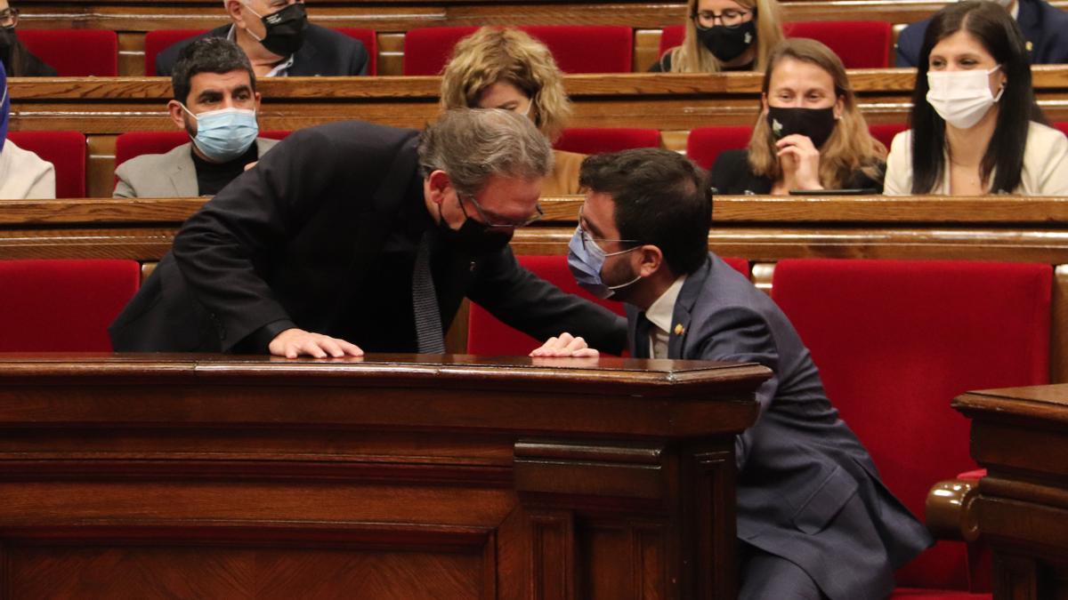 El conseller d&#039;Economia, Jaume Giró, parlant amb el president del Govern, Pere Aragonès, durant el ple del Parlament