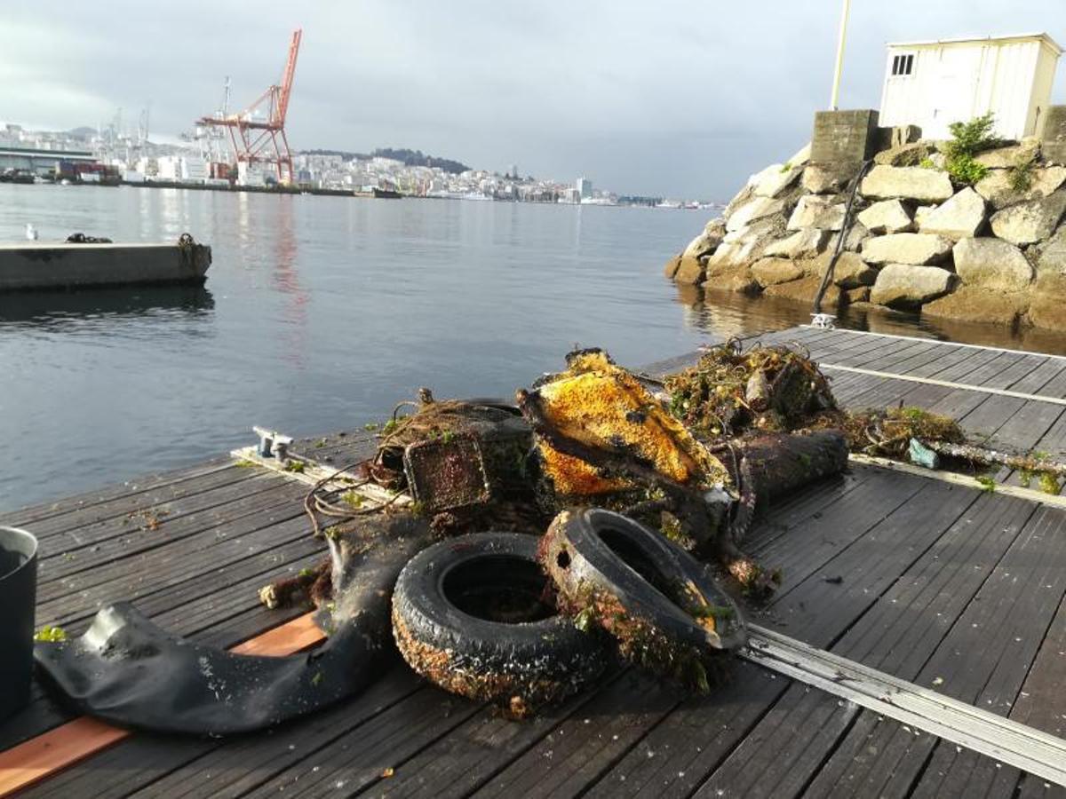 Dos trabajadores transportanen una embarcación residuoshallados en el fondo marino.