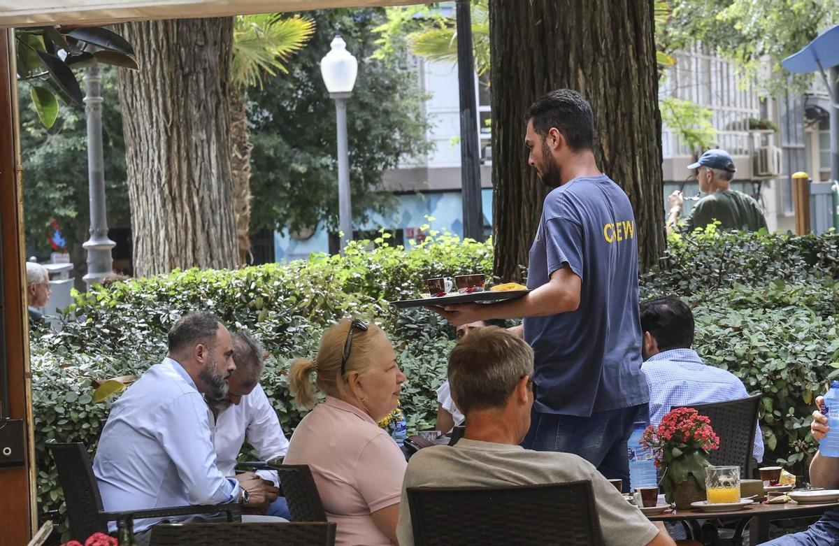 Un camarero atiende a los clientes de una terraza en la ciudad de Alicante.