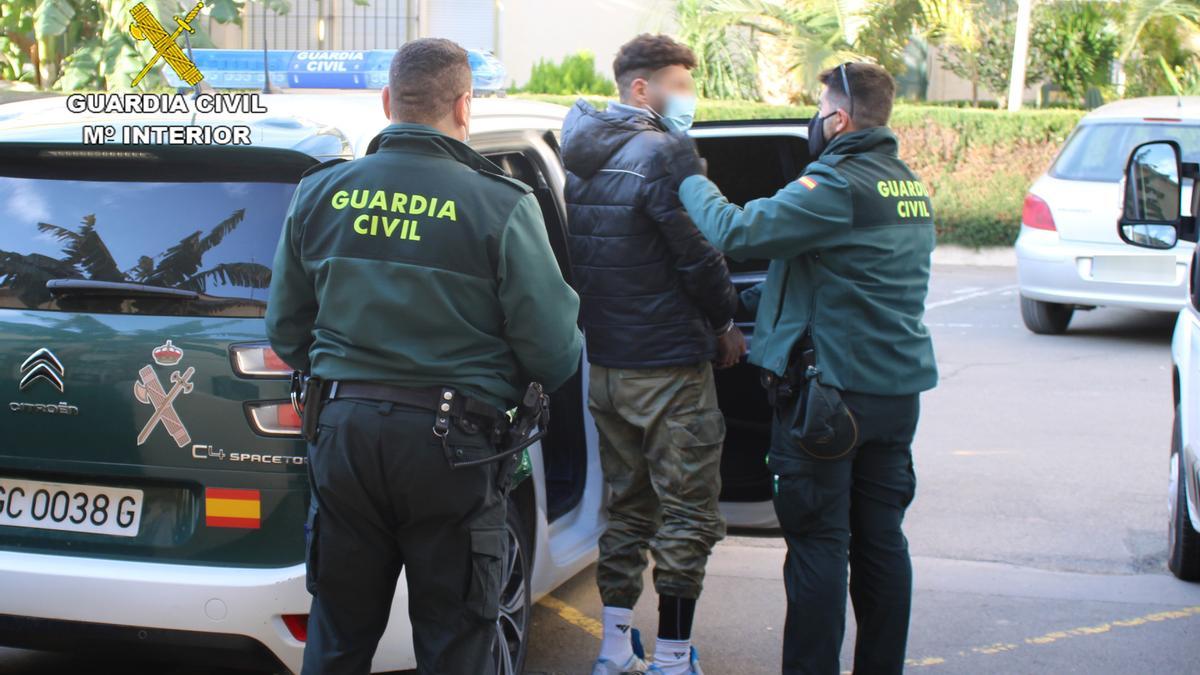 Dos guardias civiles introduciendo en el vehículo al presunto autor de los robos en La Unión.