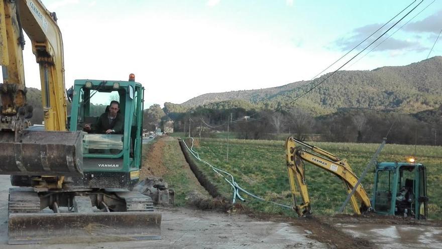 Grues treballant a la recta de la carretera GI-524 on es desplegarà la nova xarxa d&#039;aigua potable de Sant Miquel de Campmajor.