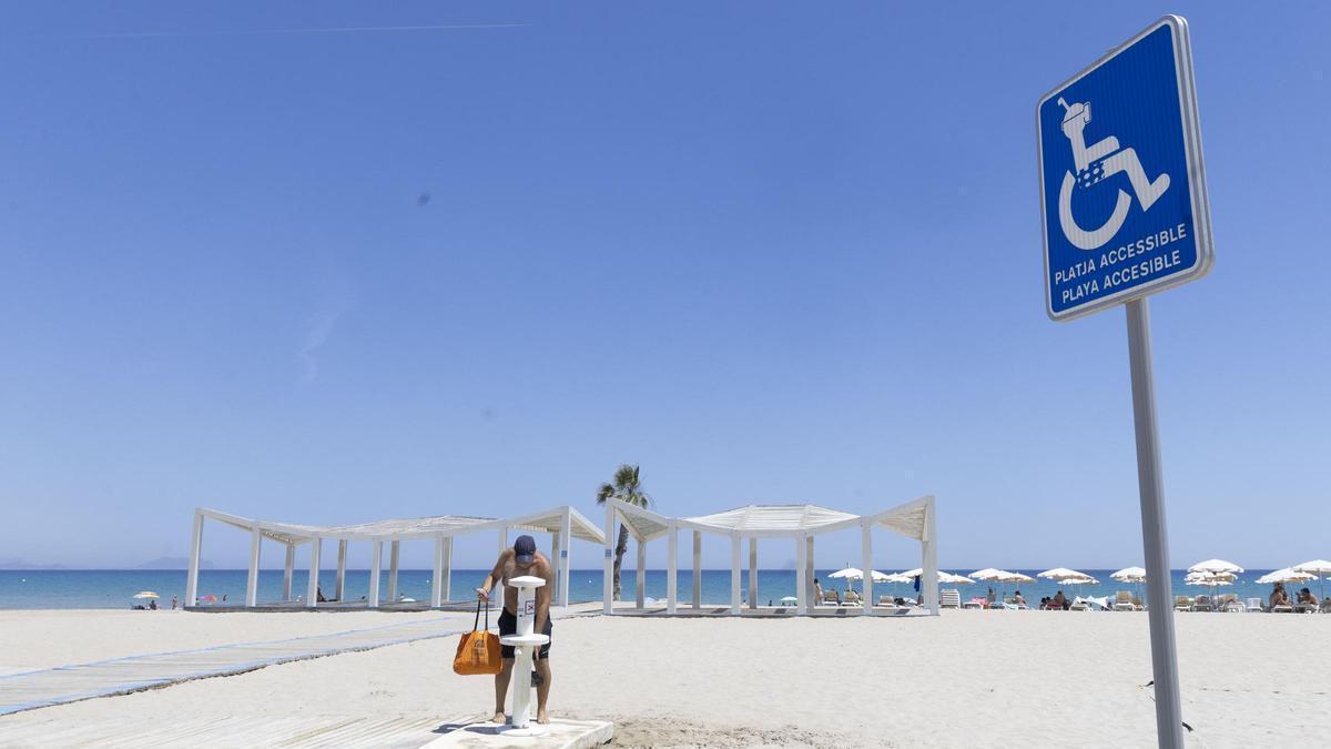 Un hombre utiliza un lavapiés, en perfecto estado, en la playa de San Juan junto a la zona de baño adaptado, que no empezará hasta dentro de un mes.