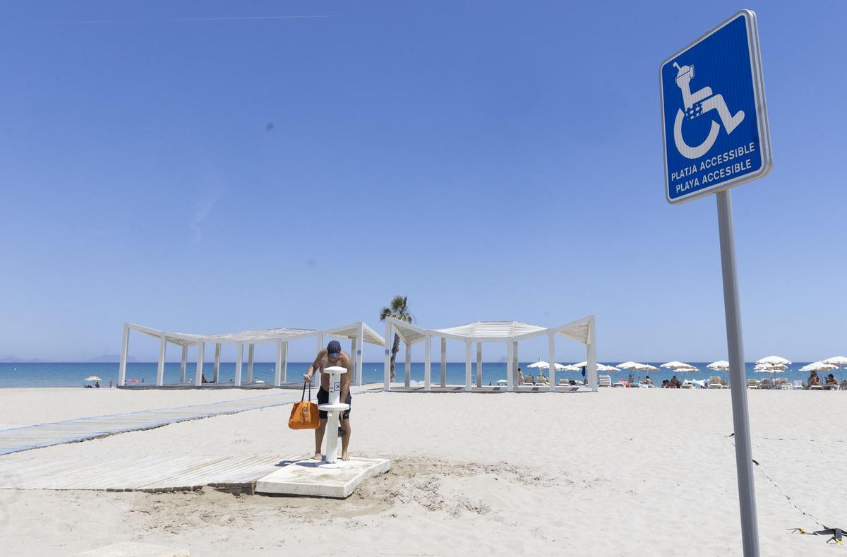 Un hombre utiliza un lavapiés, en perfecto estado, en la playa de San Juan junto a la zona de baño adaptado, que no empezará hasta dentro de un mes.