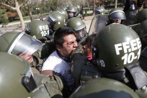 Un manifestante muerde el brazo de un policía antidisturbios al ser detenido durante una movilización contra la reforma educativa del Gobierno chileno