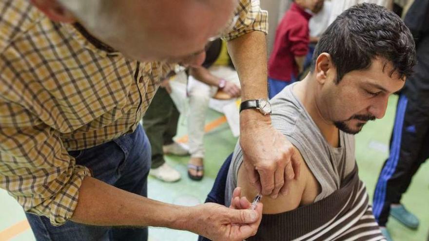 Un médico voluntario alemán vacuna a un refugiado en un centro de acogida de Stuttgart. // Efe