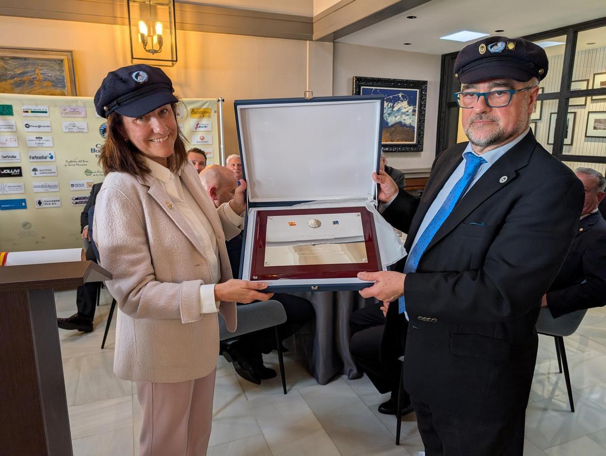 Cecilia Alvargonzález recibe con la gorra puesta la placa conmemorativa de manos del presidente Vicente Quintanilla