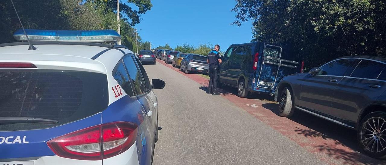 Agentes de la Policía Local, denunciando una hilera de coches aparcados sobre una senda peatonal señalizada.