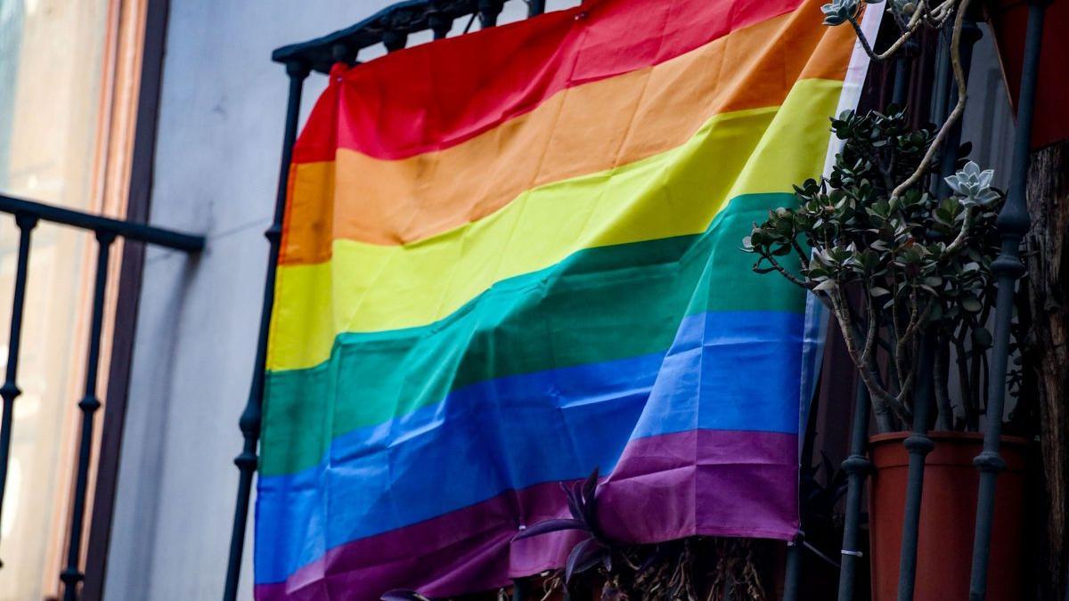 Una bandera arcoíris colgada en un balcón.