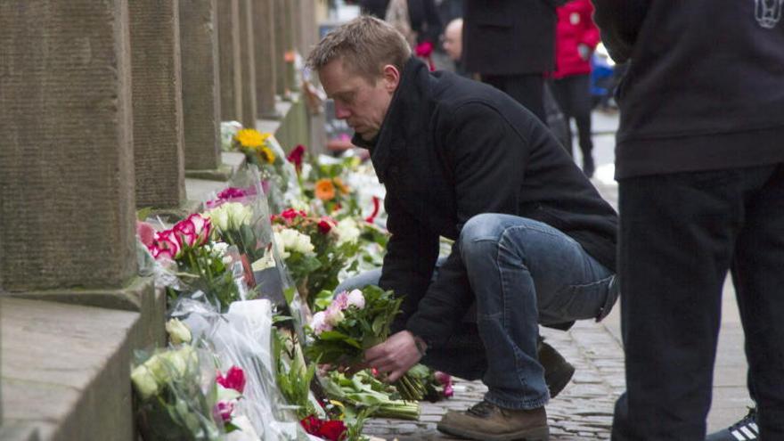 Un hombre deposita unas flores en recuerdo a los fallecidos.