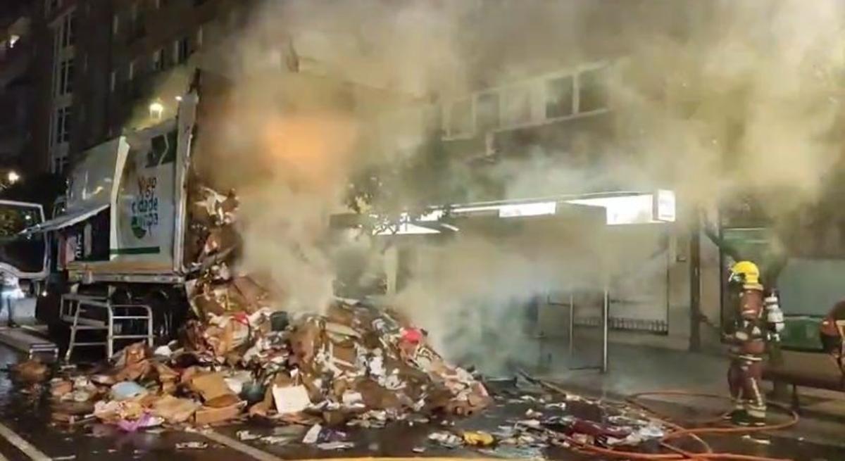 Momento en el que los bomberos apagan las llamas del camión de basura.