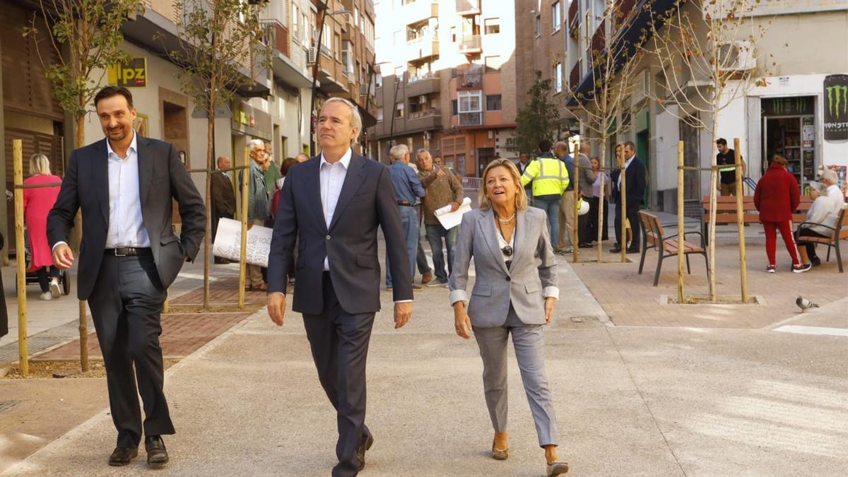 Azcón, este martes, paseando por la renovada calle Cuarte en Torrero con la protesta de los vecinos de fondo.