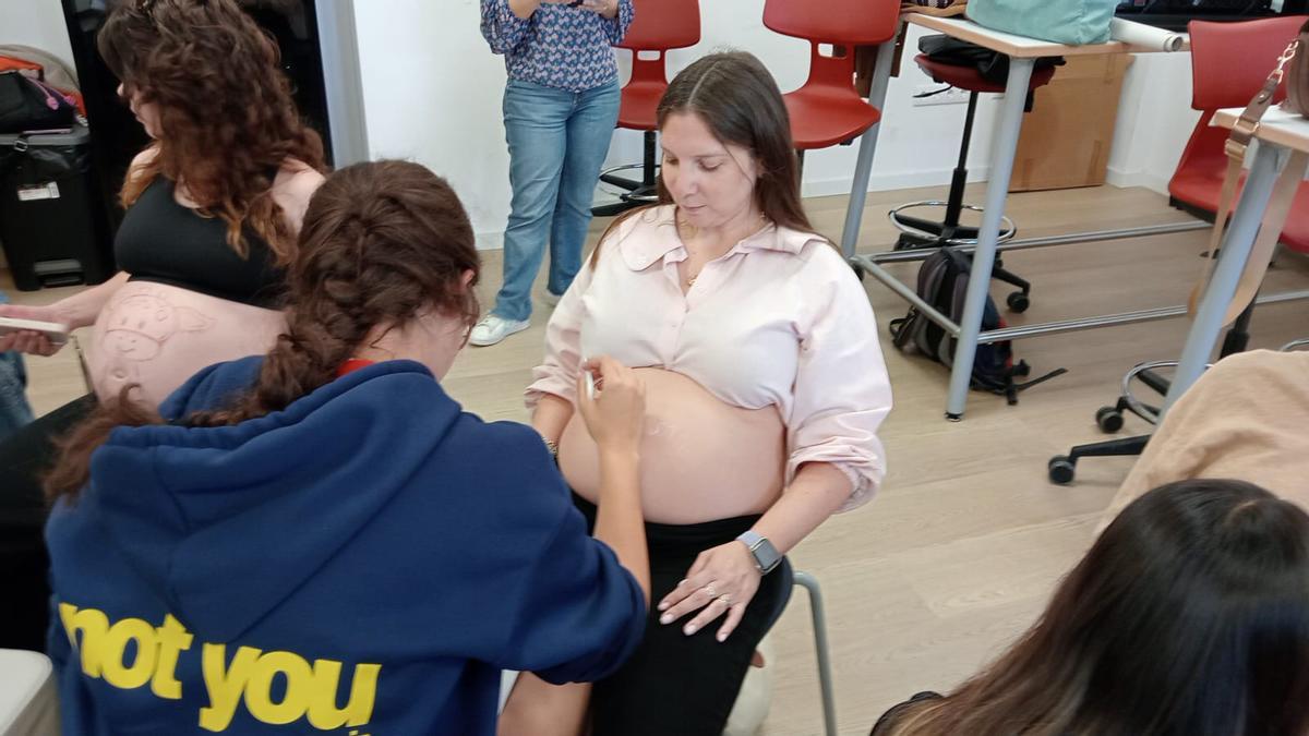 Una de las alumnas pinta la barriga a una de las participantes.