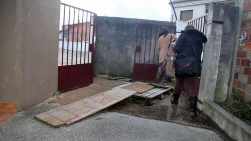 Los vecinos colocaron un tablón para acceder al centro debido al charco que se forma.  // Fotos: J. L. Oubiña