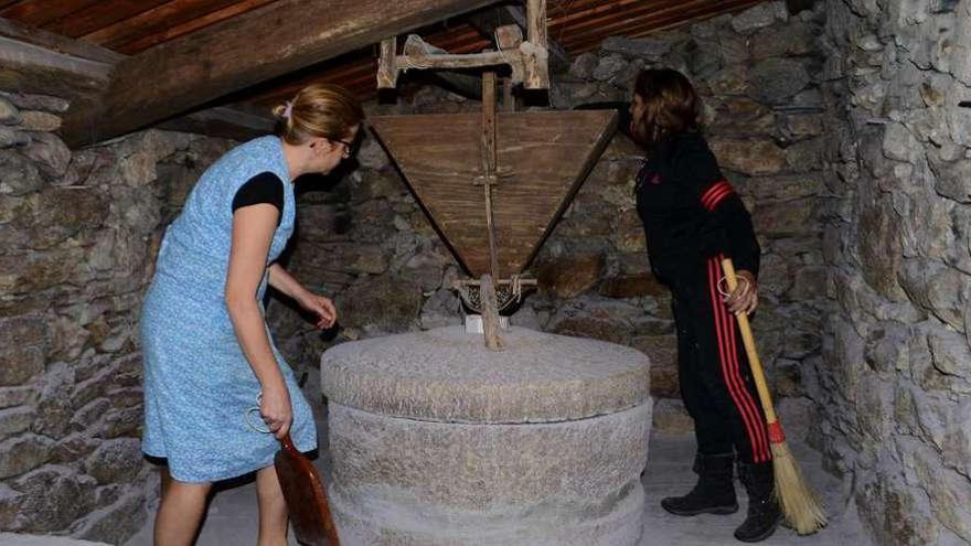 Dos integrantes de la Asociación Cultural de meiro moliendo el miércoles el millo corvo en el Molino da Presa. // Gonzalo Núñez