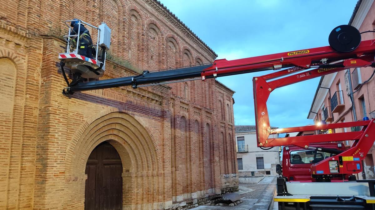Efectivos del Parque trabajan en la retirada de hierbas en la puerta de la iglesia de San Lorenzo.