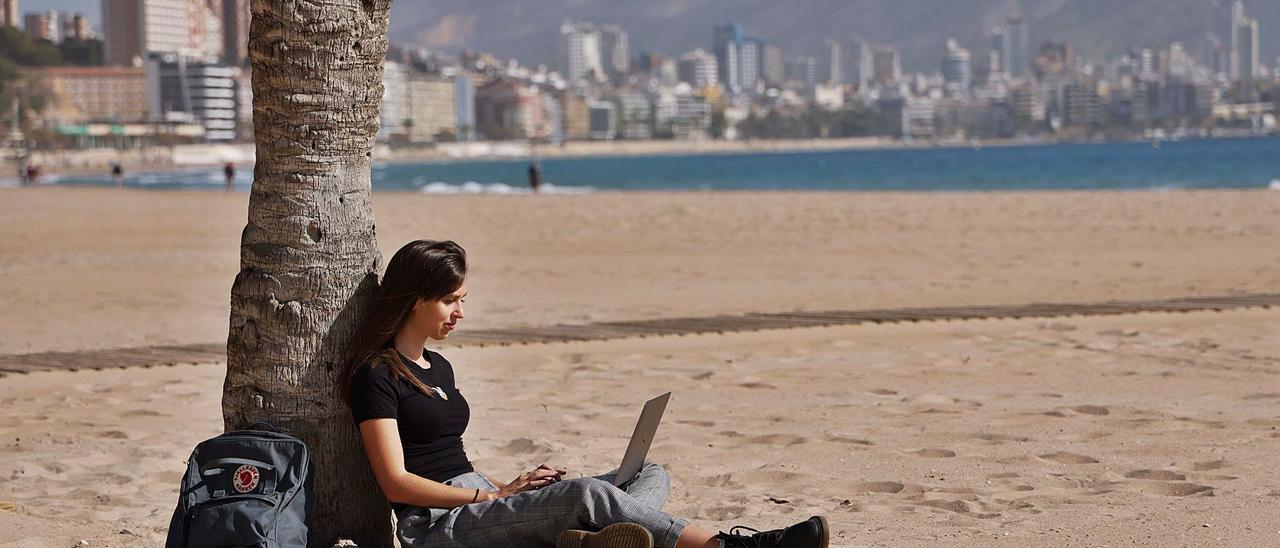 Una joven inglesa trabaja desde la playa de Benidorm con su ordenador, una de las posibilidades que tienen los «nómadas digitales». |