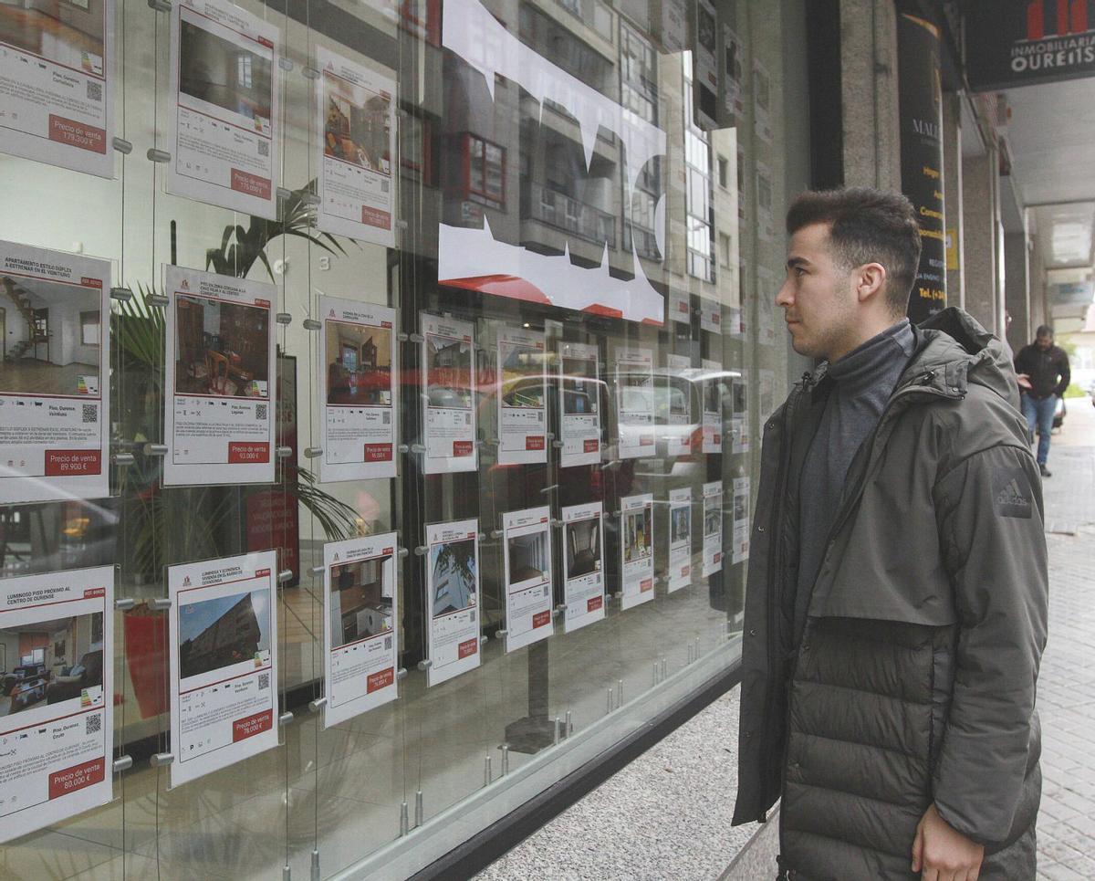 Un joven observa las ofertas del escaparate de una inmobiliaria de Ourense. | Iñaki Osorio
