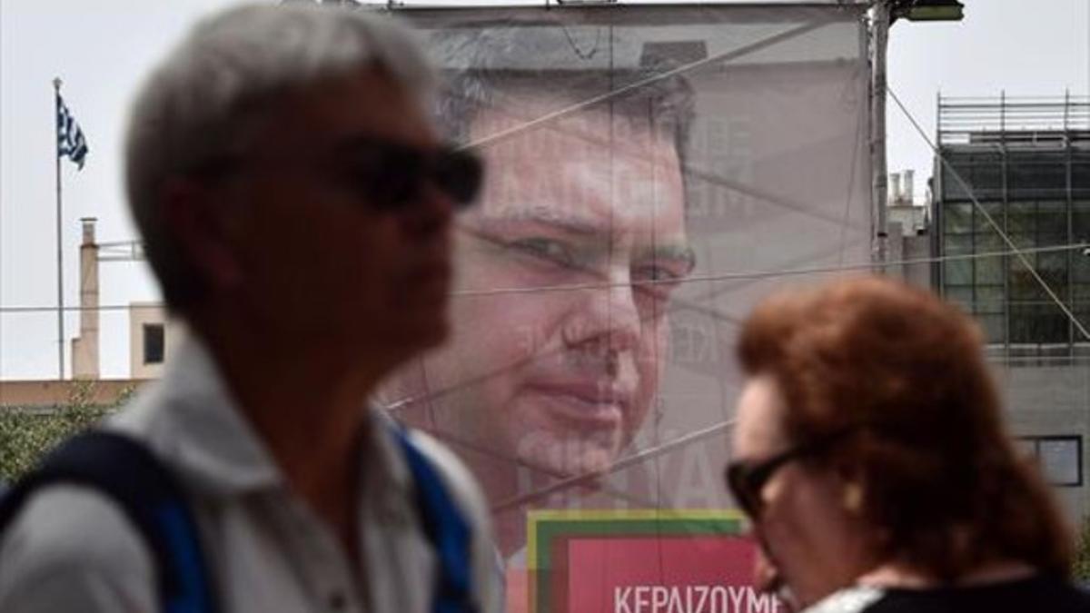 Varias personas pasan, sin mirarlo, por delante de un cartel electoral de Alexis Tsipras, en Atenas.