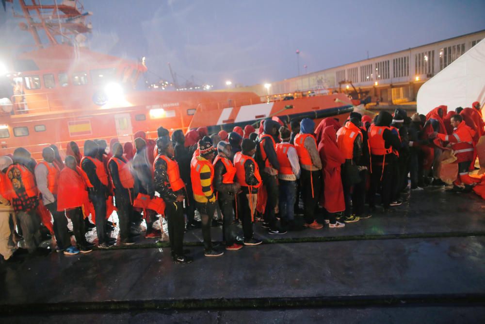 Migrants stand under the rain after disembarking ...