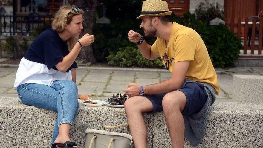 Una pareja come mejillones en la praza da Chousa. // R. V.