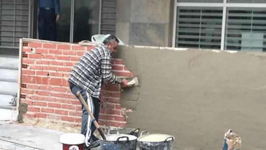 Imagen del operario enluciendo el muro del acceso del Ayuntamiento.