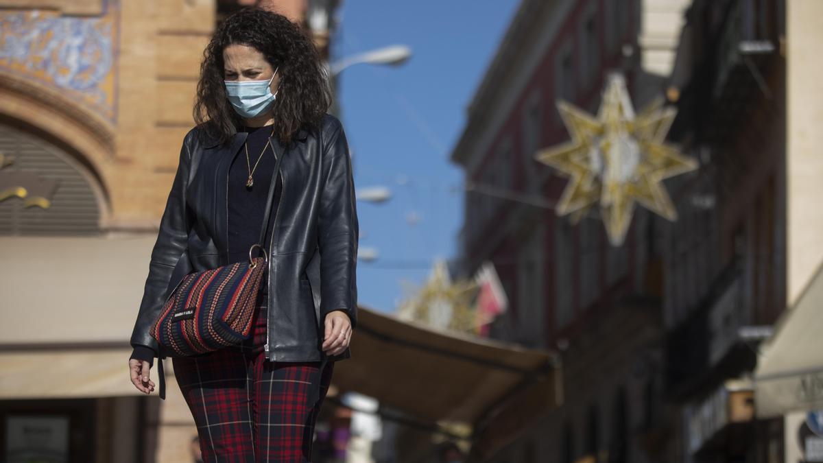 Una mujer con mascarilla camina por la plaza de San Francisco, en Sevilla.