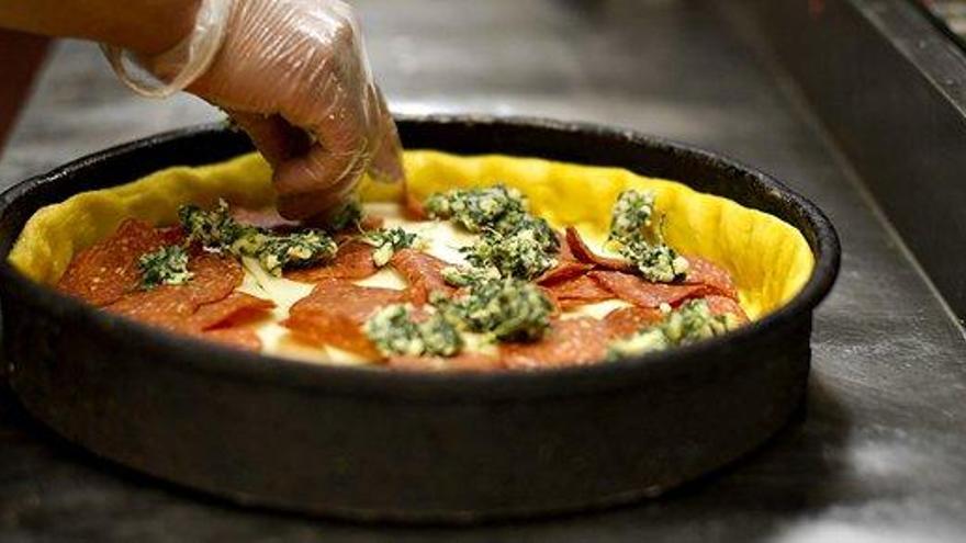 Un cocinero prepara una pizza.