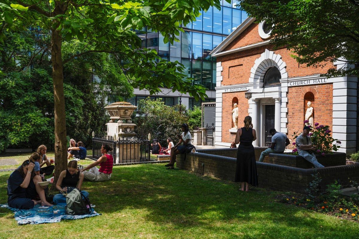 Trabajadores se resguardan del sol en un parque frente a la iglesia de Saint Botolph a la hora de la comida, este martes en Londres.
