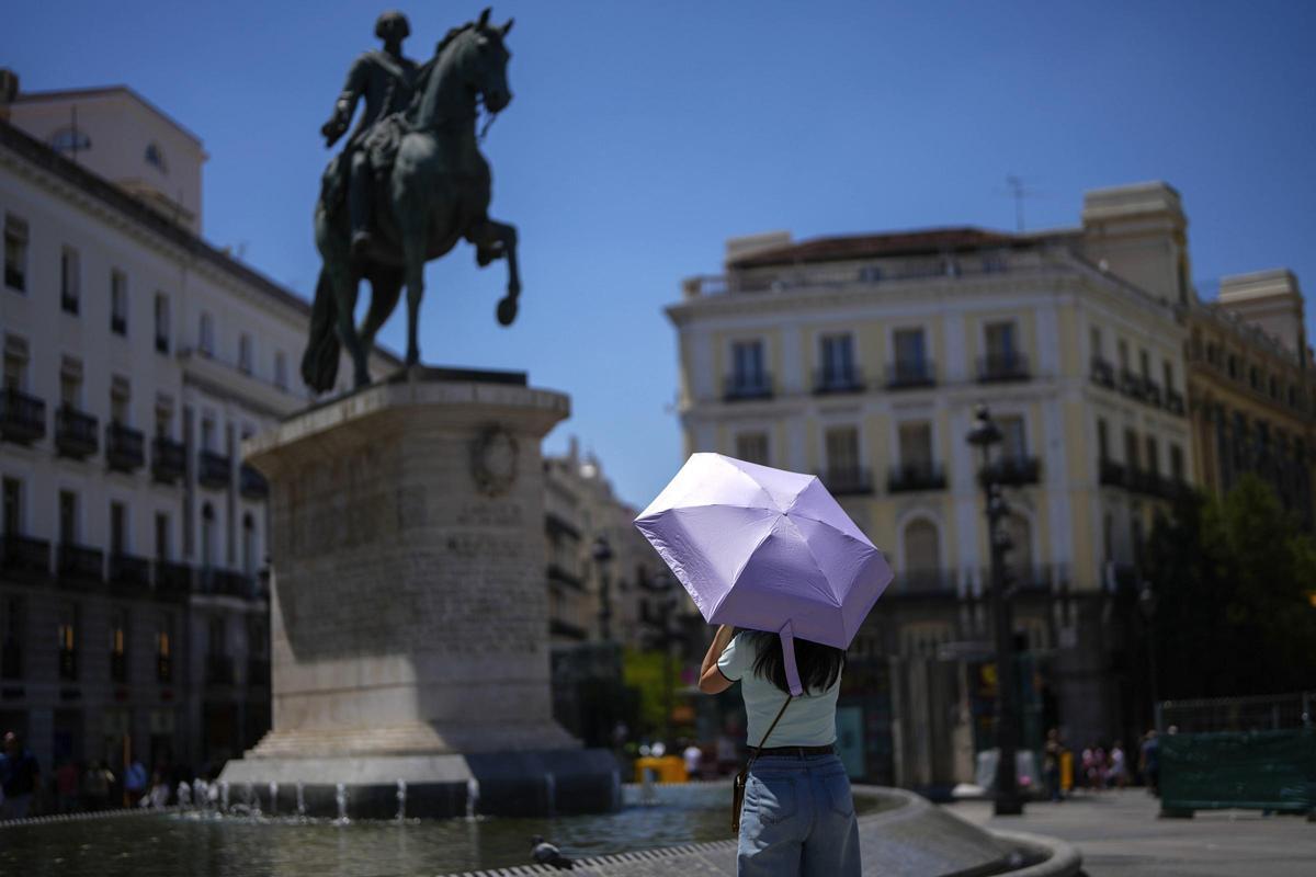 Una mujer se protege del calor con un paraguas este viernes en el centro de Madrid. Una mujer se protege del calor con un paraguas este viernes en el centro de Madrid.