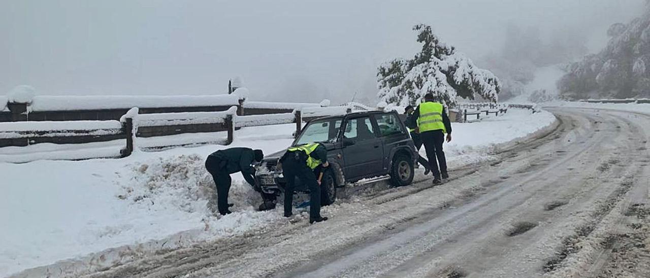 Agentes de la Guardia Civil ayudan a un conductor en plena nevada en la carretera de La Espina a Tineo, en este último concejo.| Guardia Civil