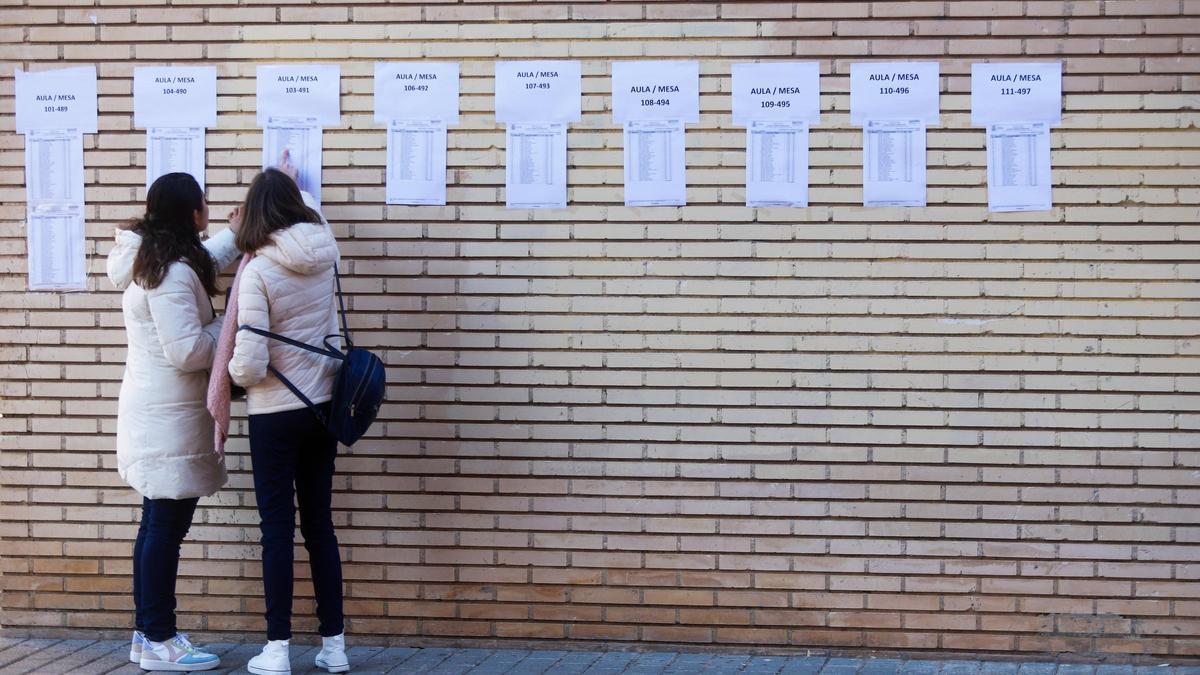 Dos aspirantes consultan su aula asignada para unas oposiciones de la Generalitat, en imagen de archivo.