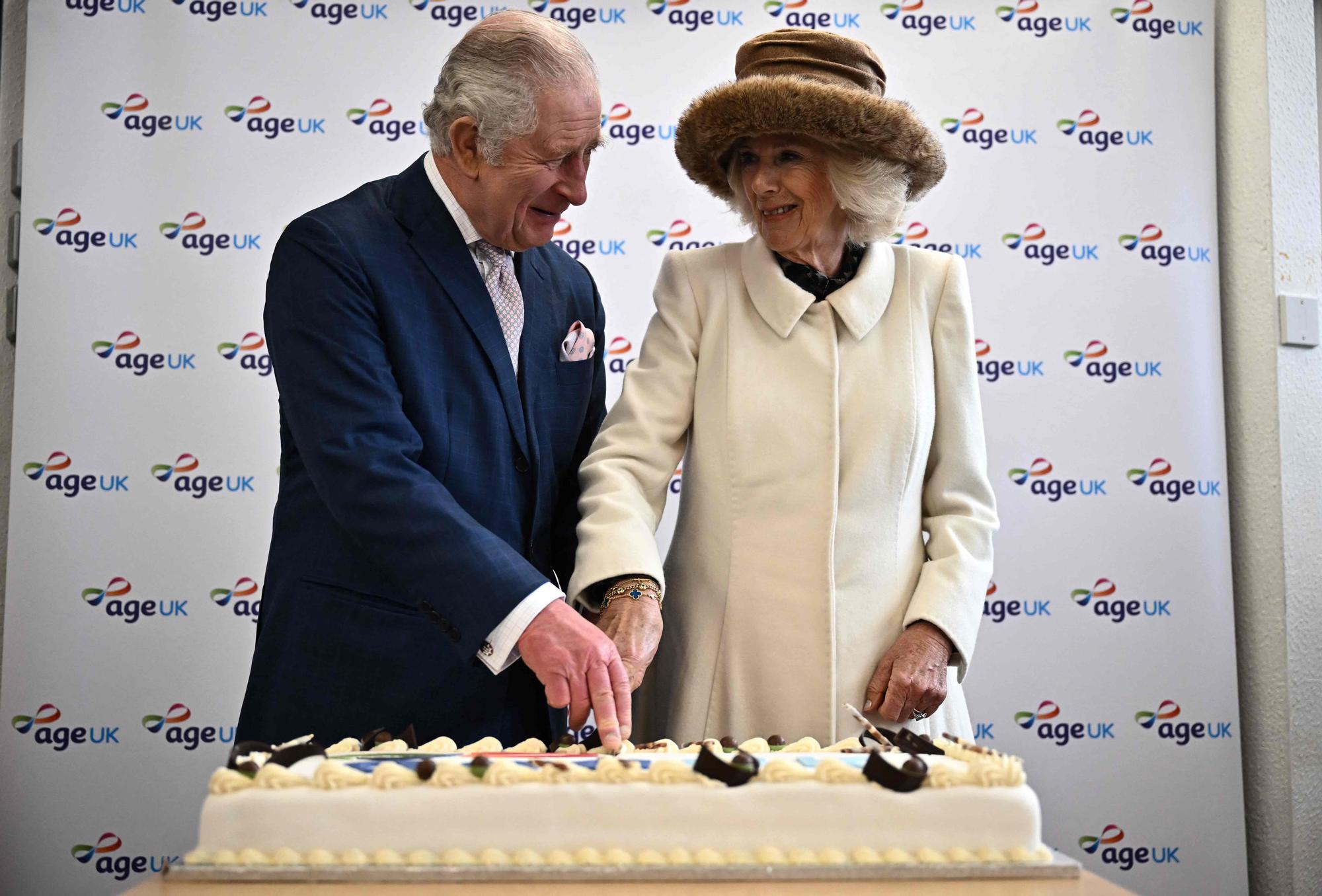 Los reyes Carlos y Camila cortan un pastel durante un acto con voluntarios y usuarios de la organización benéfica Age UK, el pasado mes de marzo.