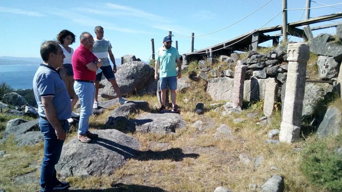 Valeriano Martínez (en primer término) con Sotelo y Loli Hermelo, observan un ara en O Facho.// Fdv