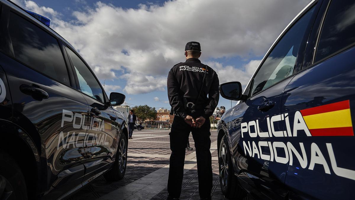 Un Agente de la Policía Nacional junto a vehículos policiales.