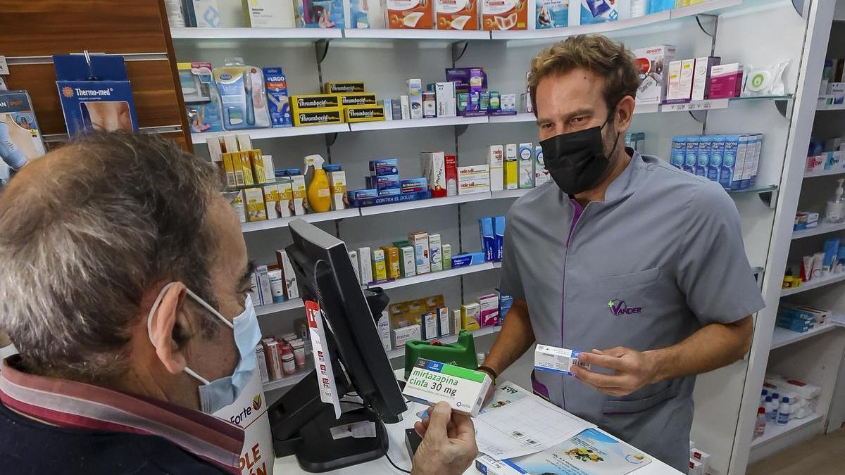 Un farmacéutico atiende a un paciente en Alicante.