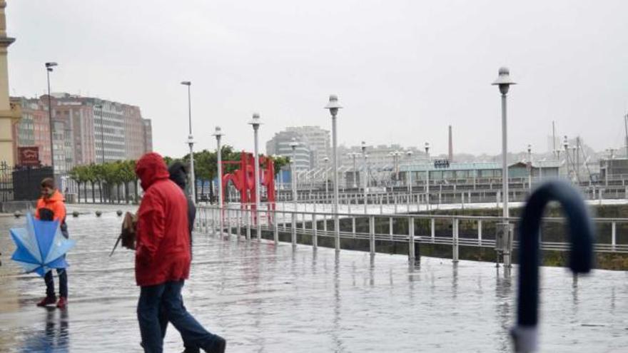 Varios paseantes, protegiéndose de la lluvia, ayer, en el puerto deportivo de Gijón.