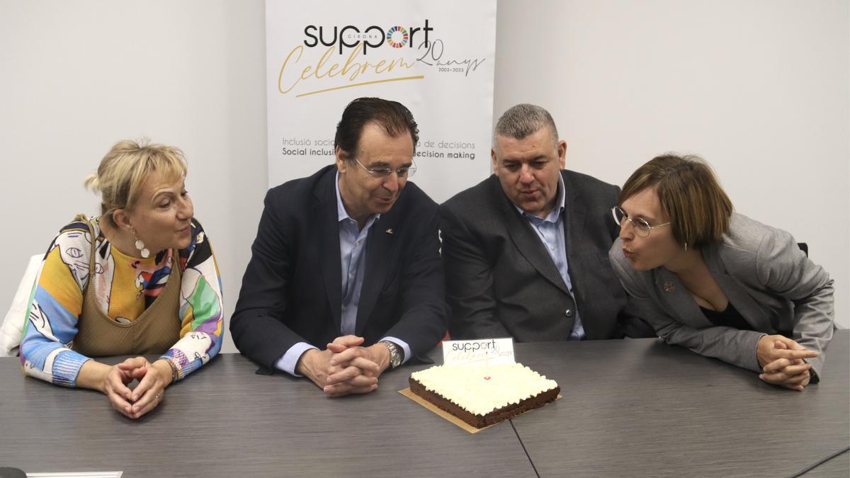 El president i el director de la Fundació Support de Girona amb dues directives més bufant l’espelma del pastís de 20è aniversari de l’entitat