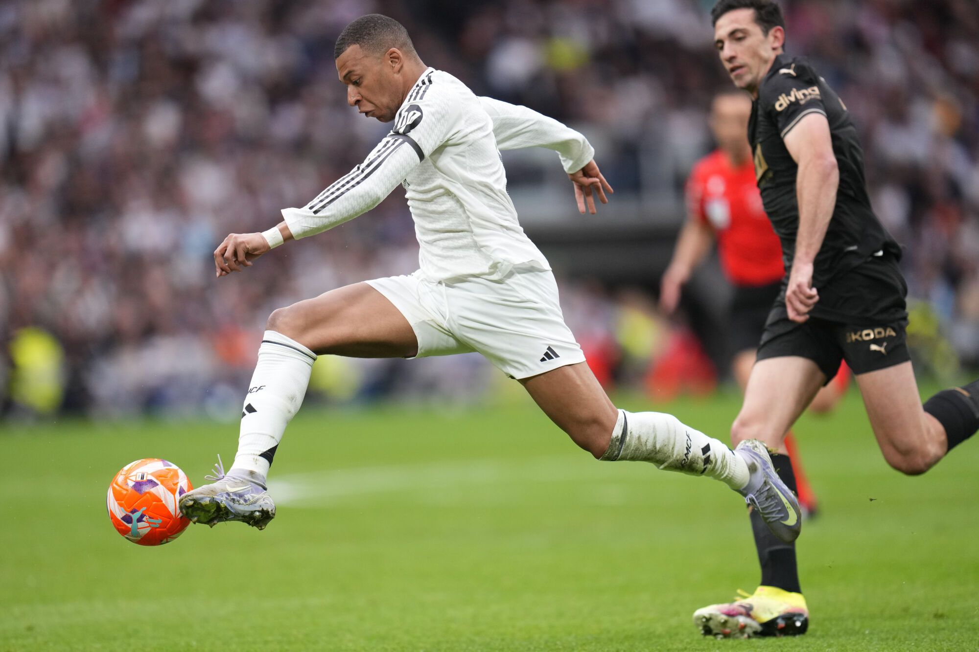 Real Madrid's Kylian Mbappe controls a ball chased by Valencia's Cesar Tarrega during a Spanish La Liga soccer match between Real Madrid and Valencia at the Santiago Bernabeu stadium in Madrid, Spain, Saturday, April 5, 2025. (AP Photo/Manu Fernandez). EDITORIAL USE ONLY/ONLY ITALY AND SPAIN