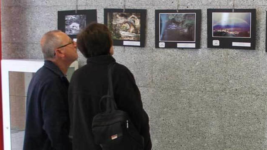 Dos visitantes de la exposición observan las fotos.