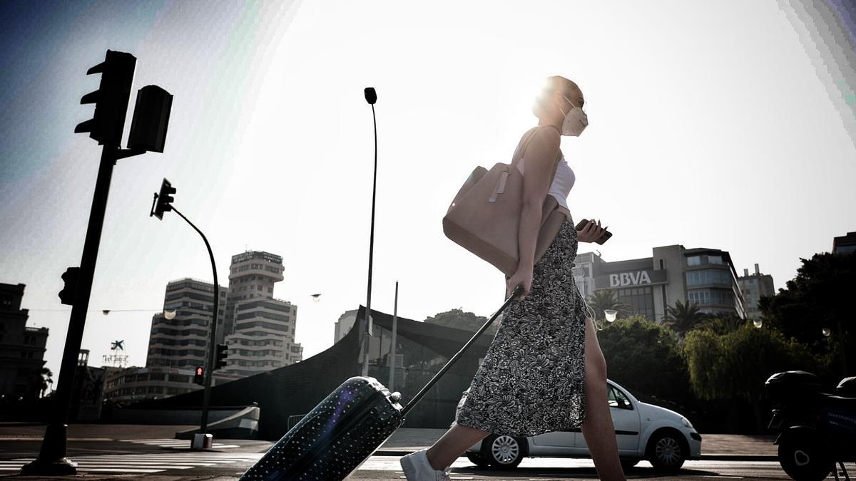 Una chica camina con una maleta en una jornada de altas temperaturas en Santa Cruz de Tenerife.